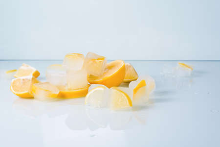 cosmetic ice cubes with lemon and vitamin C for skin care on a blue light background, natural organic ingredients for home care, detox. place for text.の写真素材