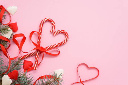 valentine's day candy lollipop in the shape of a heart with a red ribbon and fir branches on a pink background, for text place.の写真素材