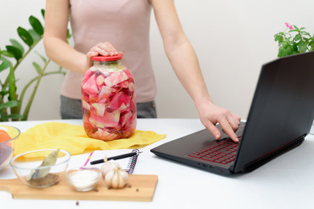 Cook at home online video recipes on a laptop Pickled pink cabbage fermentative with beets and carrots in brine in a jar.の写真素材