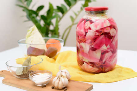 Pickled pink cabbage fermentative with beets and carrots in brine in a jar on a light backgroundの写真素材