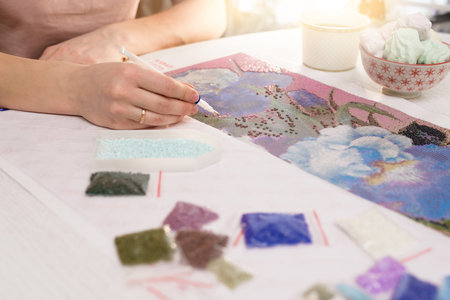 home hobby-to draw pictures of rhinestones, multi-colored diamond mosaic. the process of gluing pencil rhinestones on canvas pictures of the house on the table with tea and nuts.の写真素材