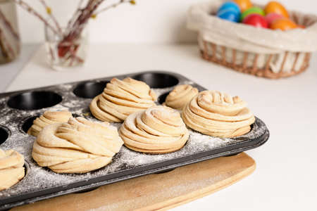 cruffins easter spring pastries, a mixture of muffin and croissant on a light background, the composition Easter painted eggs willow and cake.の写真素材