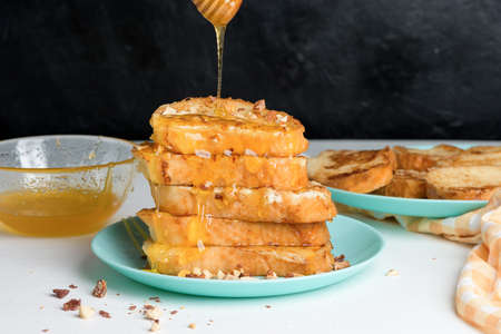 homemade French toast fried with honey and nuts on a blue plate on a dark background. soaked in milk egg mixture. healthy breakfast. levitation honey slowly.の写真素材