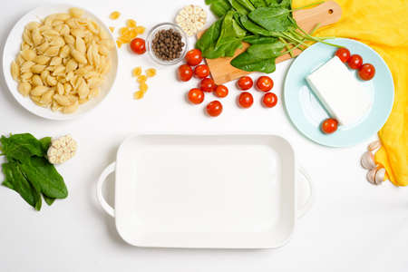 step-by-step preparation and ingredients for oven-baked feta cheese with tomatoes and pasta, pepper garlic on a light background top view, trend recipe.の写真素材