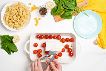 step-by-step preparation and ingredients for oven-baked feta cheese with tomatoes and pasta, pepper garlic on a light background top view, trend recipe.の写真素材