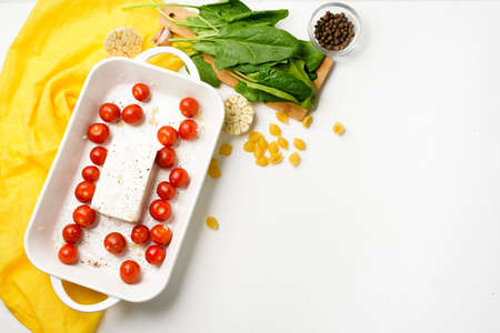 step-by-step preparation and ingredients for oven-baked feta cheese with tomatoes and pasta, pepper garlic on a light background top view, trend recipe, mixing macaroni and cheese.の写真素材