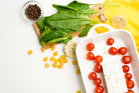 step-by-step preparation and ingredients for oven-baked feta cheese with tomatoes and pasta, pepper garlic on a light background top view, trend recipe, mixing macaroni and cheese.の写真素材