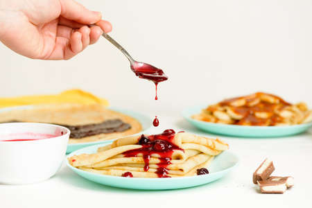 blini pancakes with red berry jam close-up on a blue plate on a light background . traditional Russian holiday is a symbol of spring and sweet dessertの写真素材
