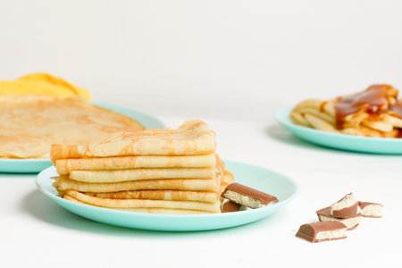 blini pancakes with banana and caramel, close-up on a blue plate on a light background . traditional...