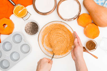 step-by-step recipe for pumpkin cupcakes in a baking dish with chia seeds, autumn orange pie with orange. ingredients for pumpkin pie top view . mixing ingredients by a womans handの写真素材