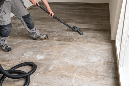 A man sucks water from the tiled floor with the vacuum cleaner.の写真素材