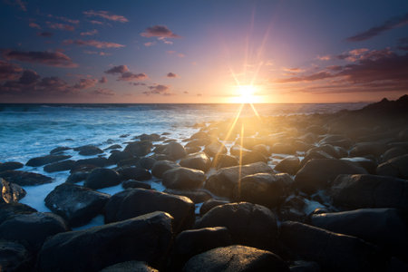 sunrise with interesting full of rocks foreground and nice clouds color in backgroundの写真素材