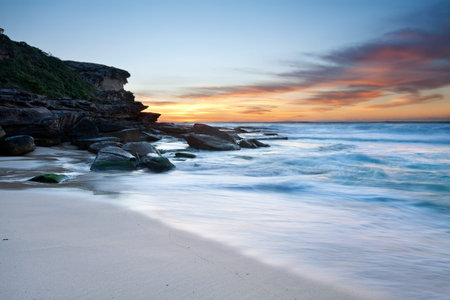 australian beach at dawn with cliff face in backgroundの写真素材
