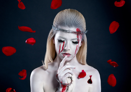girl with a bloody face, with white skin and a wreath on her head. barbed wireの写真素材