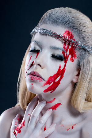 girl with a bloody face, with white skin and a wreath on her head. barbed wireの写真素材
