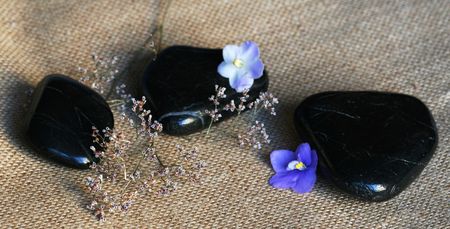 Spa black stones with lilac flowers on sackcloth backgroundの写真素材
