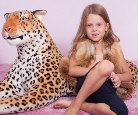 Little girl and toy leopard on pink floorの写真素材