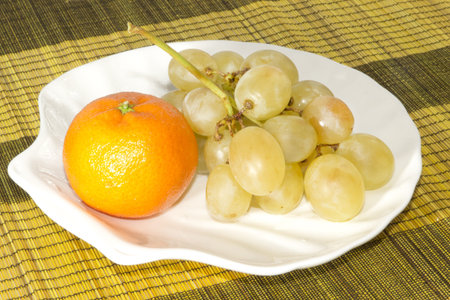 Mandarin and grapes on the plate in the form of shells