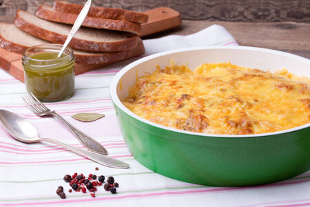 casserole with mushrooms and cabbage in frying pan with fresh bread, pesto, pepper and pepper mill on linen tableclothの写真素材