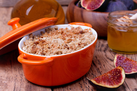 apple and figs crumble  in orange ceramic dish  with honey on wooden backgroundの写真素材