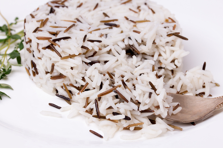 Fork and mixed cooked rice with thyme on white plate. Basmati and wild rice mix.の写真素材
