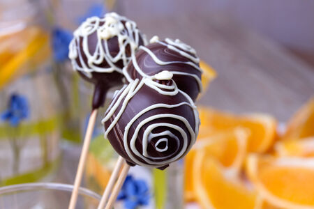 Chocolate Cake pops on the sticks in glass with oranges, wooden backgroundの写真素材