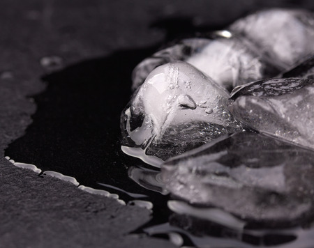 Ice melting on black slate plate with reflectionの写真素材