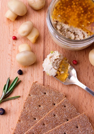 Chicken pate in jar and crispbread with champignon and rosemary on wood cutting boardの写真素材