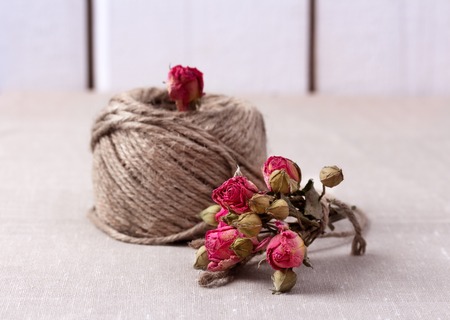 Valentines and mothers day background. Ball of twine with bouquet of dried roses on sackcloth background. Concept of natural style design. Copy space.の写真素材