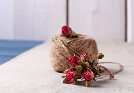 Valentines and mothers day background. Ball of twine with bouquet of dried roses on sackcloth background. Concept of natural style design. Copy space.の写真素材