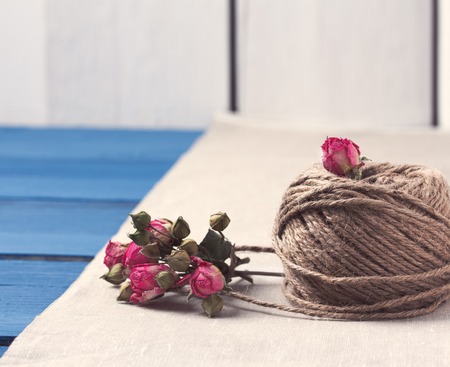 Valentines and mothers day background. Ball of twine with bouquet of dried roses on sackcloth background. Concept of natural style design. Copy space.の写真素材