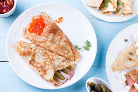 Thin pancakes, crepes with red caviar, salmon, pickled cucumbers and baconの写真素材