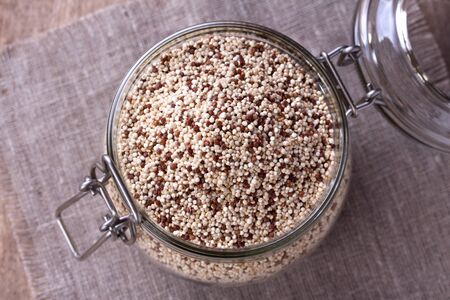 uncooked quinoa in the glass jar on the sackclothの写真素材