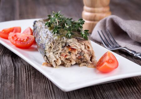 Mackerel fish stuffed with rice and vegetables. Old wooden table.の写真素材