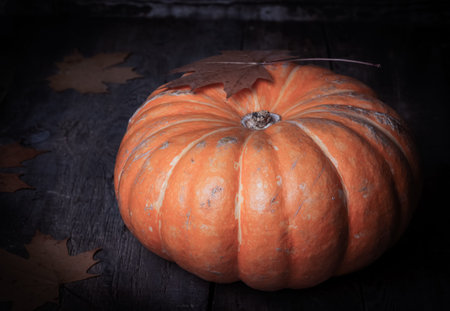 autumn halloween pumpkin with fallen leaves on wooden backgroundの写真素材