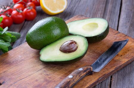 Sliced avocado and knife on old cutting board. Guacamole ingredients.の写真素材