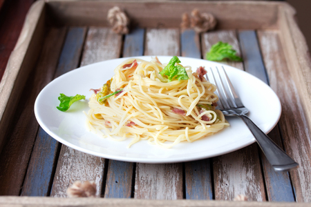 Italian pasta with cheese, prosciutto and basil on vintage rustic wooden backgroundの写真素材