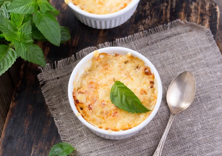 mushroom and potato gratin in white ceramic bowls, on wooden rustic backgroundの写真素材