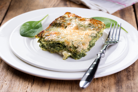 Portion of tasty spinach Lasagna. Top view. Rustic wooden background.の写真素材