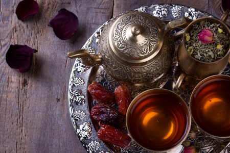 Traditional arabic tea set and dried dates. Old wooden backgroundの写真素材