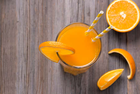 Glass of freshly pressed orange juice with sliced orange half on wooden tableの写真素材