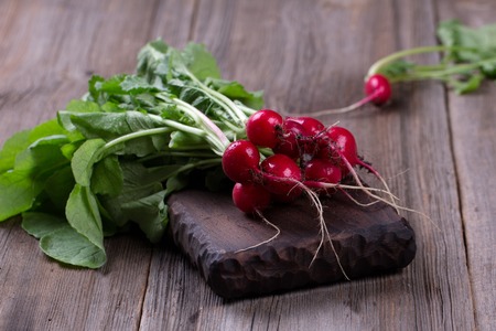 Bunch of fresh radishes on old wooden tableの写真素材