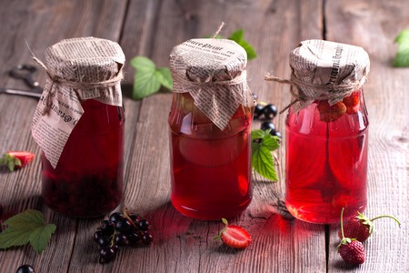 Canned homemade apple and berry compotes in glass jars. Old wooden desk. Rustic. Vintage.の写真素材