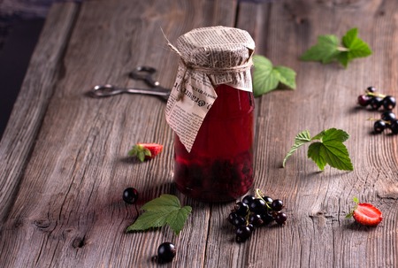 Canned homemade apple and berry compotes in glass jars. Old wooden desk. Rustic. Vintage.の写真素材