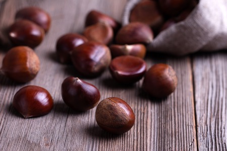 fresh chestnuts in sack bag on the old wooden tableの写真素材