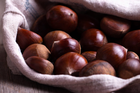fresh chestnuts in sack bag on the old wooden tableの写真素材