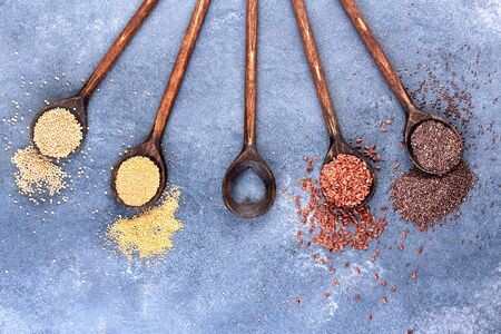 collection of healthy grains in wooden spoon on stone textured background. Chia seeds, grain amaranth, and flaxseeds.の写真素材