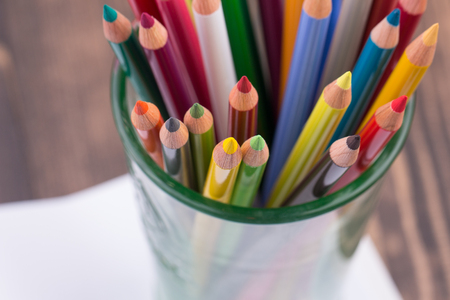 Multicolored pencils in a glass on wooden backgroundの写真素材