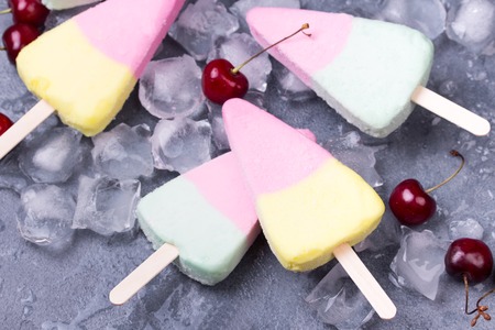 Homemade ice cream or popsicles and cherry with ice on concrete table, frozen fruit juice, horizontal, top viewの写真素材