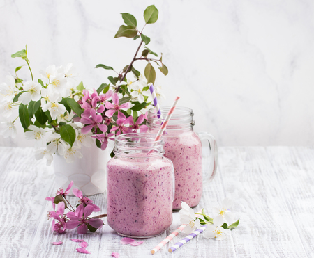 Healthy berry smoothie or milkshake in jar with apple blossom on white wooden rustic background. Healthy lifestyle and weight loss concept.の写真素材